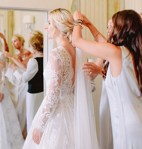 Bride getting her veil on after having her hair and makeup done by Tuscany Bridal Beauty Stylists with her reflection in the mirror